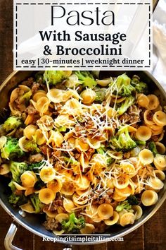 pasta with sausage and broccoli in a skillet on top of a wooden table