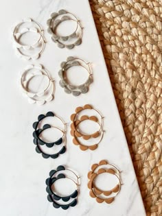 six pairs of hoop earrings sitting on top of a white table next to a straw hat