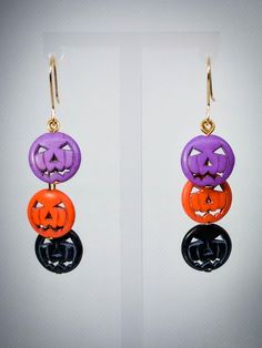 halloween earrings with pumpkins and jack - o'- lanterns hanging from hooks on white background