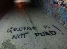 graffiti is spray painted on the ground near a wall with writing that says grunge is not dead