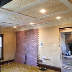 a room that is being remodeled with wood flooring and exposed ceiling tiles on the walls