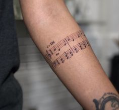 a person with a tattoo on their arm has musical notes tattooed on it's arm