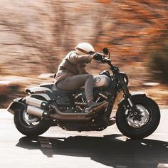 a man riding on the back of a motorcycle down a curvy road with trees in the background