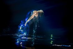 a man standing on top of a surfboard in the ocean under water at night