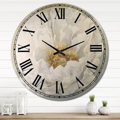 a large clock with white flowers painted on it's face and hands, sitting on a shelf