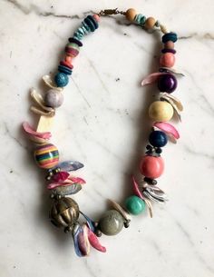 - Funky, vintage, colorful shell and bead necklace - Purchased in the 1980s, quintessential 80s style necklace and jewelry - Dyed shell pieces and beads - Chunky necklace - Variety of beads: rainbow, brass, turquioise, navy blue, pink - Really eye-catching. - Fun Christmas or holiday idea for someone who loves loud, eye-catching jewelery pieces - This is in excellent condition Details about the item: Please see photos for a detailed description, and don't hesitate to ask about any imperfections Vintage Multicolor Wooden Beads Jewelry, Vintage Multicolor Beaded Necklaces, Vintage Multicolor Necklaces With Colorful Beads, Vintage Multicolor Beach Jewelry, Funky Colorful Beaded Jewelry, Bohemian Rainbow Beaded Necklaces With Wooden Beads, Bohemian Rainbow Beaded Necklace With Wooden Beads, Vintage Multicolor Beads For The Beach, Adjustable Multicolor Shell Necklace With Colorful Beads