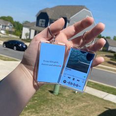 someone is holding up two key chains in front of a house with the ocean on them