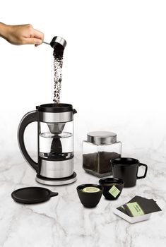 a person is pouring coffee into a french press with other items around it on a marble surface