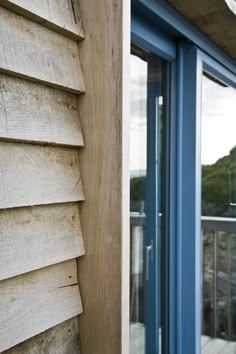 the side of a house with wooden siding and blue glass doors on it's sides