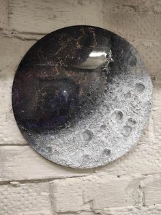 a black and silver plate sitting on top of a white brick wall with holes in it