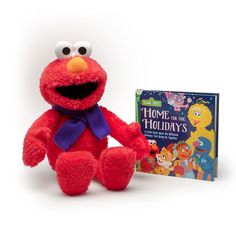 a red stuffed animal sitting next to a children's book and toy sesame street