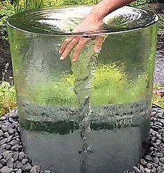 a large glass vase sitting on top of a pile of rocks next to a pond