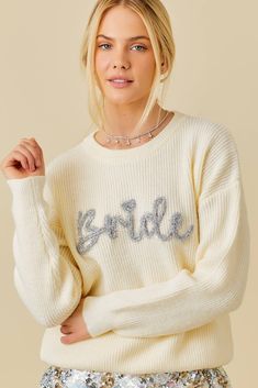 a woman wearing a white sweater with the word bride on it and sequins