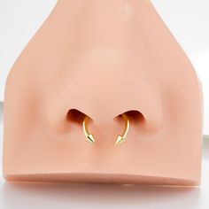 two small gold hoop earrings sitting on top of a pink plastic object with a white background