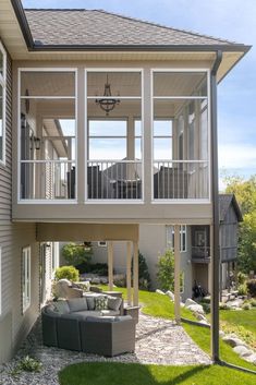 the back side of a house with an outdoor seating area and deck on top of it