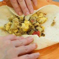 two hands reaching for an uncooked tortilla