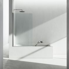 a white bathroom with a shower, sink and mirror on the wall next to it