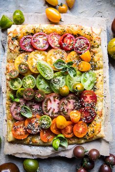 a square pizza with tomatoes, cucumbers and sprinkles on it