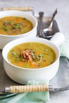 two white bowls filled with soup sitting on top of a table next to silverware