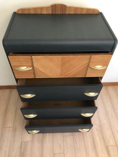 a black and wood dresser with gold handles on it's sides, sitting on a hard wood floor