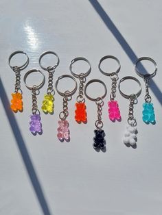 six key chains with different colored teddy bears attached to them, on a white surface