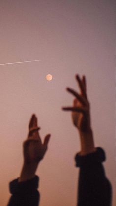 two people are flying a kite in the sky with their hands up and one person is reaching for it