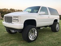 a white truck parked on top of a lush green field