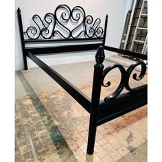 a black metal bed frame sitting on top of a floor next to a white wall