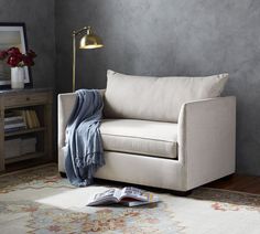 a living room with a couch, lamp and book on the floor in front of it