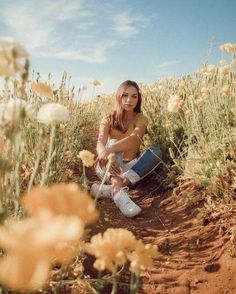 a woman sitting in the middle of a flower field