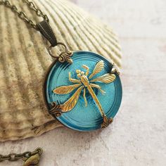 a blue glass pendant with a yellow dragonfly sitting on it's back end