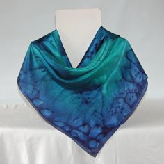 This square silk scarf measures 35 by 35 inches or 90 by 90 centimeters. It will drape around the shoulders or go over the head. It has hand rolled and hand stitched edges into which I sew my own label. The scarf is hand washable and washing instructions are included. I sprayed ponge 5 silk with emerald green and navy blue steam fix dyes. I dropped salt onto the wet dye and then I applied heat which makes the salt pull the dye into a unique pattern. The scarf was then steamed to fix the dye. A s Blue Elegant Rectangular Silk Scarf, Elegant Blue Rectangular Silk Scarf, Blue Shawl Scarf For Gift, Blue Silk Scarf As Gift, Blue Square Scarves For Gifts, Blue Square Scarves As Gift, Silk Rectangular Scarves As Gift, Silk Scarf Gift In Rectangular Shape, Square Silk Scarf For Gifting