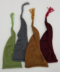 three knitted hats are lined up on a white surface