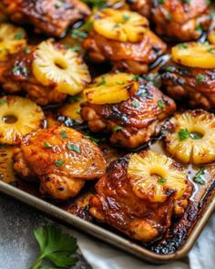 chicken with pineapples and onions on a baking sheet, garnished with parsley