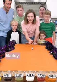 a group of people standing in front of a table with bottles of juice on it