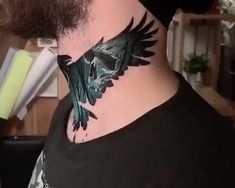 a man with a tattoo on his neck has a skull and wings design on it