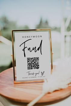 a wooden table topped with a sign and a white feather