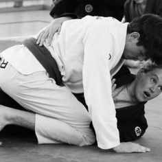 two men in white shirts and black pants are wrestling on the ground with each other