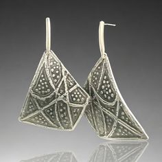 pair of silver earrings with intricate designs on them