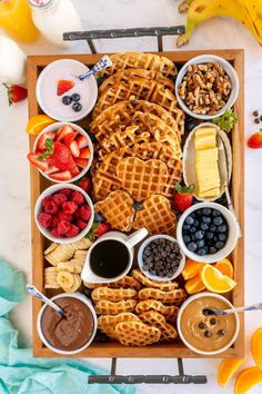 a wooden tray topped with waffles, fruit and other foods next to bananas