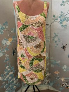 "1960's Disco queen dress covered with an abstract design of pastel colored sequins sewn on a knit dress. Yummy pale pink, rose pink, peach, yellow, antique, gold, silver and lime green iridescent, sequins dance across this spectacular party dress. The pale, pink nylon and lace slip has snaps in holders at the 1 inch shoulder straps and fits perfectly under the knit dress. Size 12, bust 36\", waist e4\", hips 36\", shoulder to hem 37\". Dry clean" Elegant Multicolor Sequin Dress For Spring, Vintage Pink Sequined Dresses, Pink Vintage Sequin Dress, Vintage Pink Sequin Dress, Vintage Sequin Dresses For Spring, Vintage Fitted Pastel Dresses, Fitted Vintage Dress In Pastel, Fitted Vintage Dresses In Pastel Colors, Glamorous Spring Sequin Dress