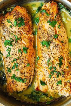 two fish fillets with herbs and seasoning in a pan