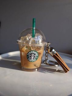 a starbucks drink in a plastic cup with a keychain attached to it, sitting on a table