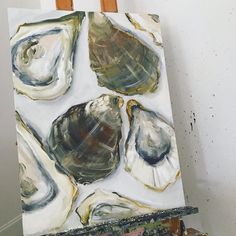 an easel is holding up a painting of seashells on white canvases