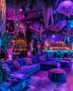 an elaborately decorated room with purple couches and palm trees hanging from the ceiling