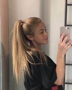 a woman is taking a selfie with her cell phone in the bathroom while wearing a ponytail