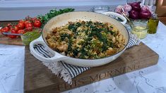 a large casserole dish on a cutting board with tomatoes, onions and spinach