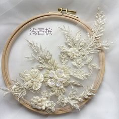 a close up of a embroidery on a white cloth with flowers and leaves in it