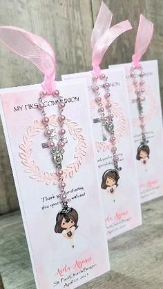 two necklaces with pink ribbon and tags attached to them on a wooden table next to a wall