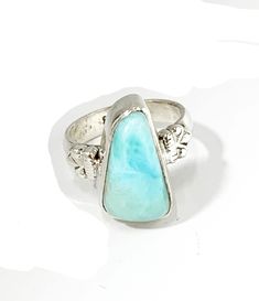 This sterling silver ring is set with a beautiful ocean blue larimar gemstone.  Larimar come only from the Dominican Republic and is famous for it's special color.  No two larimar gems are alike. The larimar measures about 16mm x 9mm and has a high dome.  It is set in a bezel accented on either side with a fleur de lys design.  Size 7 and it can be sized.   Please get in touch with any questions you may have - I am here to help! We have been in the jewelry business in Arizona for over 30 years. We have many pieces in our brick and mortar store not listed here, so please get in touch if you are looking for something special. And check back to our Etsy shop - we are always adding new pieces! Blue Larimar Opal Ring, Larimar Turquoise Gemstone Ring For Anniversary, Larimar Turquoise Ring Gift, Turquoise Larimar Ring Gift, Larimar Turquoise Ring Gemstone Gift, Gift Turquoise Larimar Ring, Turquoise Larimar Ring As Gift, Turquoise Larimar Ring For Gift, Handmade Blue Turquoise Larimar Ring